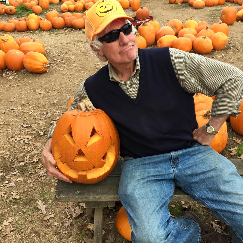 man posing with carved pumpkin at pumpkin patch