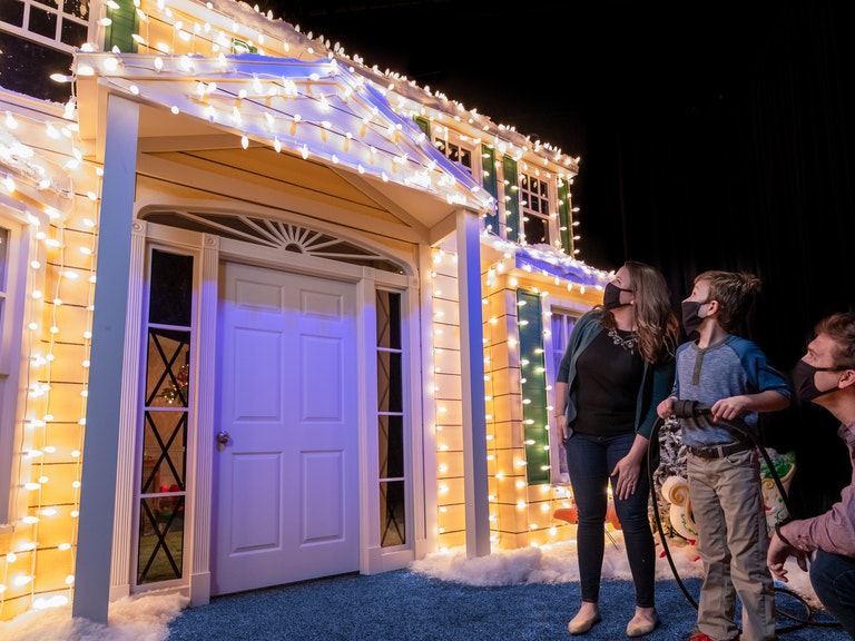 Family outside of a recreation of the house from National Lampoon's within an interactive light display 
