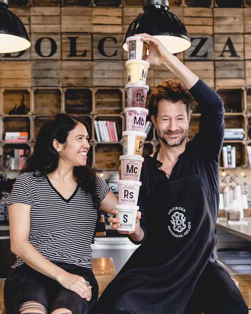 Co-owner, Violeta, smiling at husband, Robb, as he holds a tower of gelato